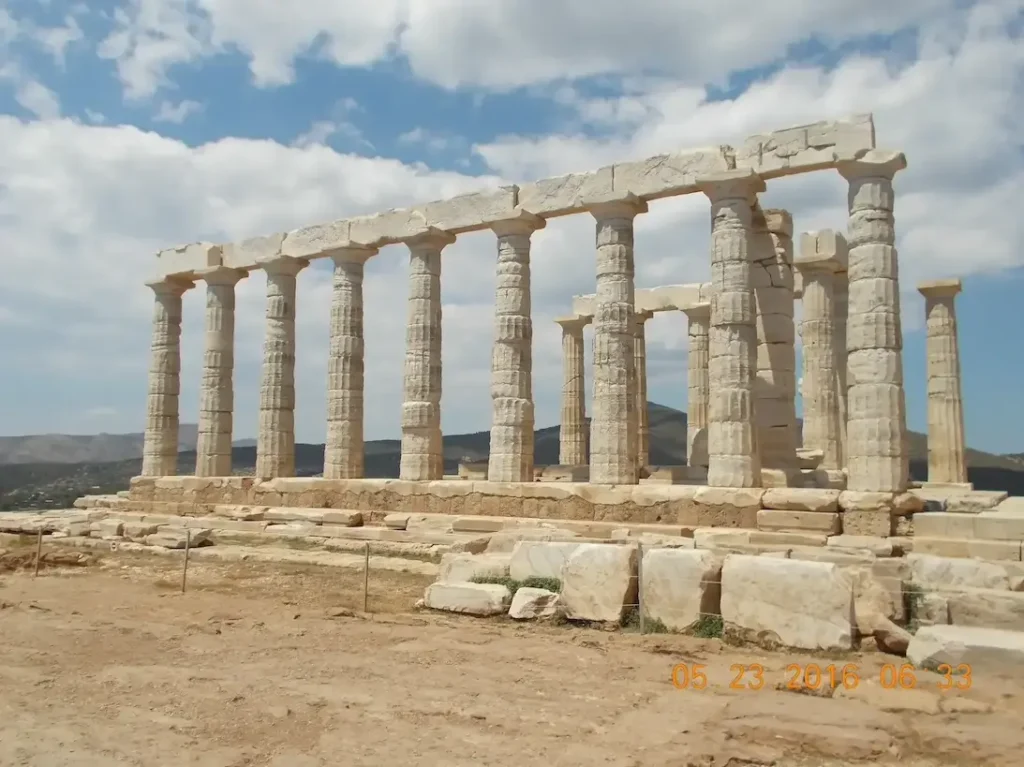 Ancient Greek Temple Ruins under Blue Sky with Clouds at Cape Sounion, Greece.