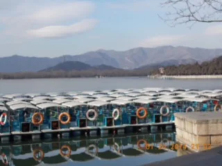 Row of pedal boats docked by a scenic lakeside with mountain views in the background.