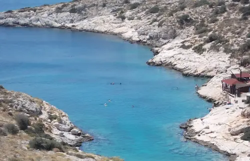 Crystal clear turquoise waters in a serene rocky cove, perfect for swimming and relaxation.