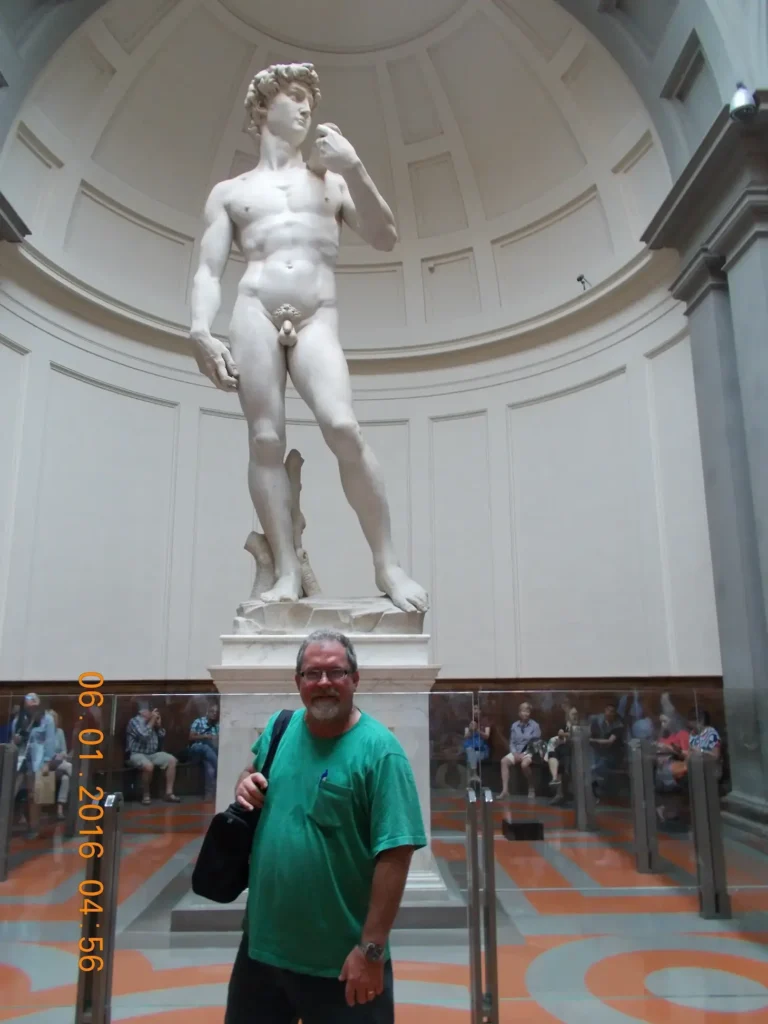 Man standing in front of Michelangelo's David statue at Florence museum.