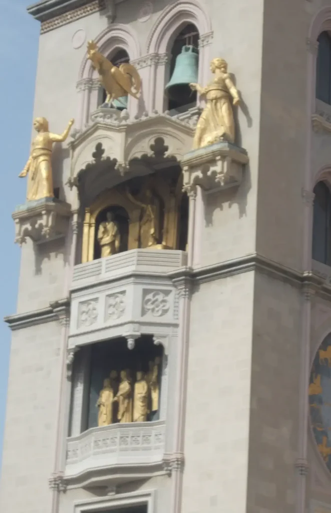 Golden statues on an ornate clock tower facade with intricate architectural details and historical sculptures.